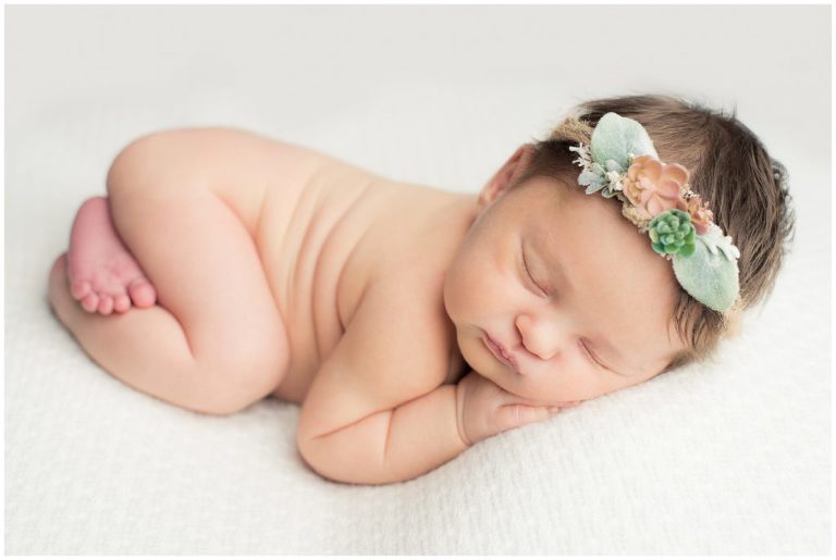Newborn baby girl poses with a succulent headband.