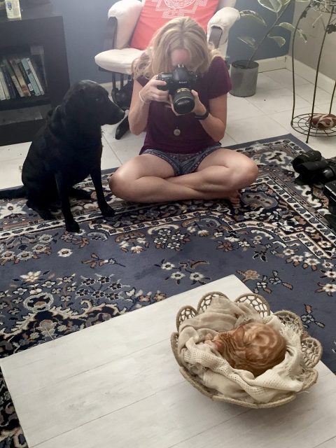 A photographer and a black lab photograph a baby kitten